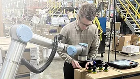 Robotiq cobot palletizer in use by male worker.