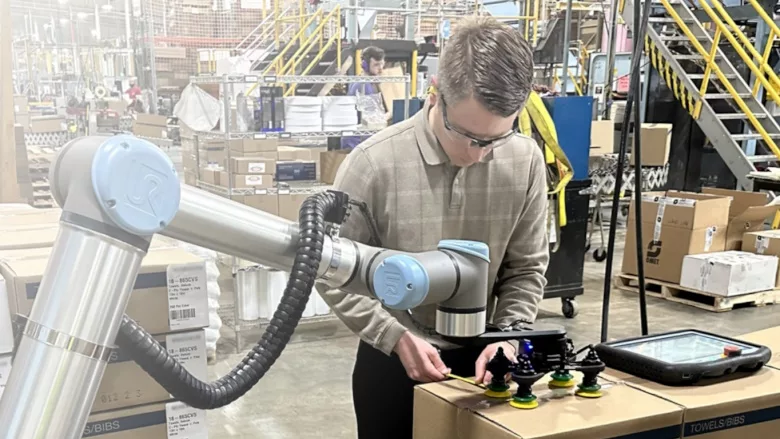 Robotiq cobot palletizer in use by male worker.