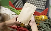 Hands holding a flexible pouch over a shopping cart