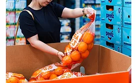Shopper lifts bulk bag of oranges