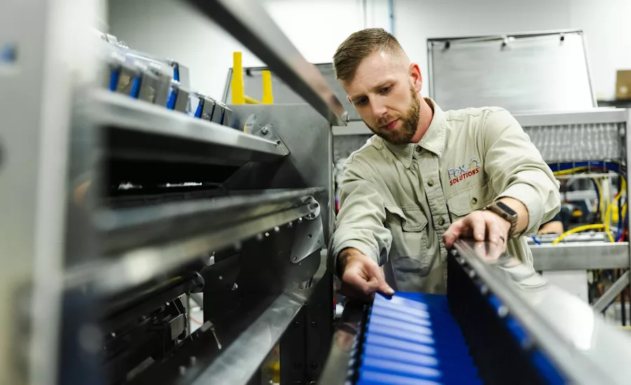 Technician reviews the cross conveyor on a Newtec weigher inside the Fox Solutions facility.