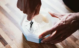 Consumer spooning out ice cream from plastic container