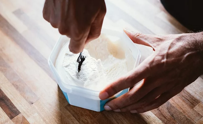 Consumer spooning out ice cream from plastic container