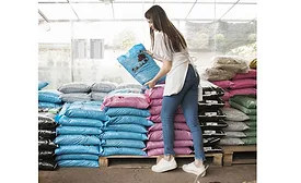 Woman working with large bags of gardening materials at greenhouse
