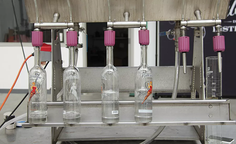 Valentine Distilling bottles are placed by hand on the 6-head semi-automatic filler
