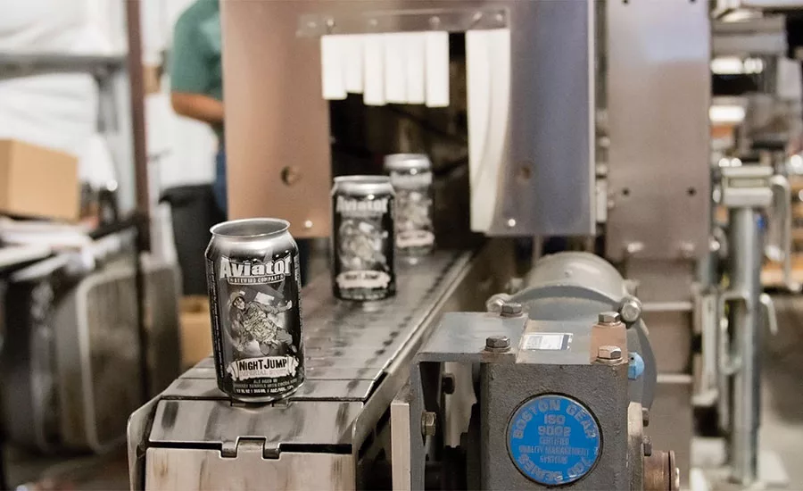 Cans come out of the heat tunnel of the Axon EZ-100 Shrink Sleeve Applicator