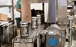 Cans come out of the heat tunnel of the Axon EZ-100 Shrink Sleeve Applicator