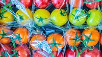 Retail display with fresh plastic wrapped cherry tomatoes.