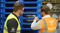 Image of an Avery Dennison employee and a Tosca employee examining reusable plastic pallets.