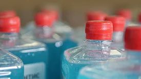 Conveyor with many bottles with blue liquid and red lids.