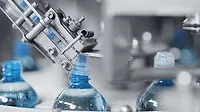 Machinery putting caps on blue water bottles.