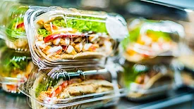Chilli chicken with pita, pre-packaged sandwiches displayed in a commercial refrigerator.