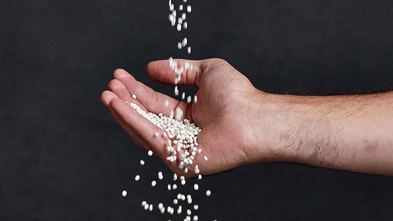 Image of hand catching falling pellets made of recycled polyethylene (rPE).