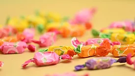 A variety of fruit candies in different colors on yellow background