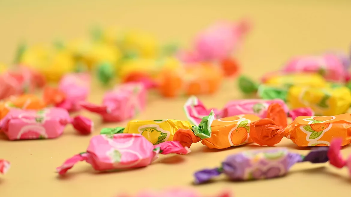 A variety of fruit candies in different colors on yellow background