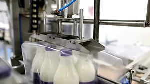 Machine packing six plastic bottles with milk Machine packing six plastic bottles with milk.