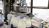 Machine packing six plastic bottles with milk Machine packing six plastic bottles with milk.