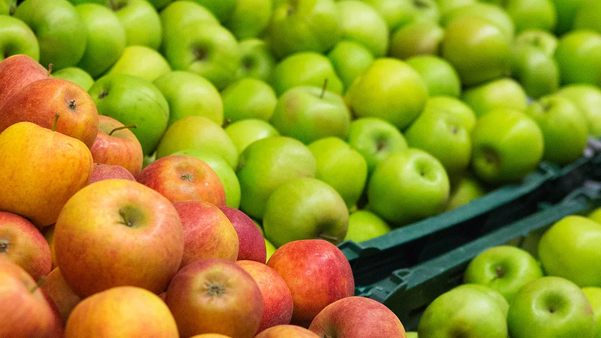 A variety of apples in the grocery store produce aisle.
