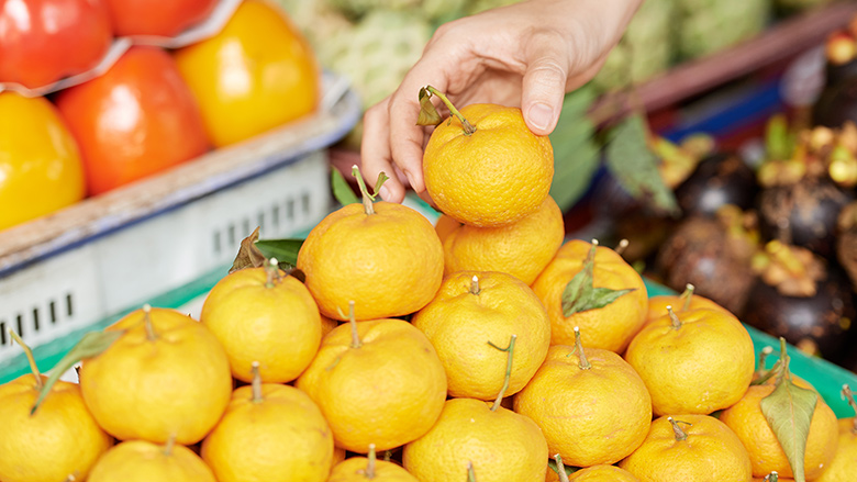 A hand picking up a tangerine.