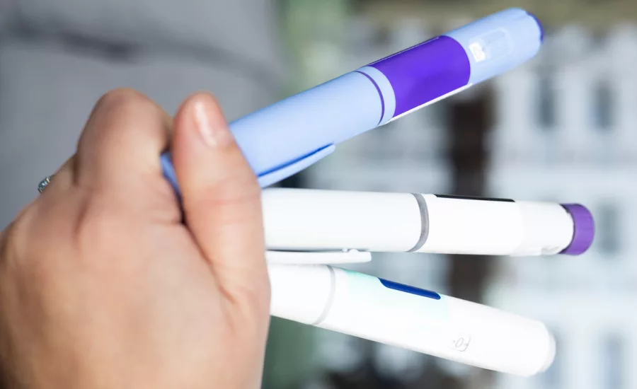 Hand Holding Various Semaglutide and Insulin Injection Pens for different stages of the treatment.